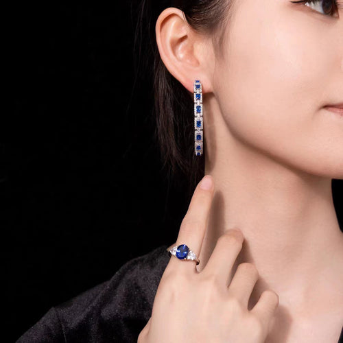 Lady wearing Blue sapphire silver drop earrings with moissanite