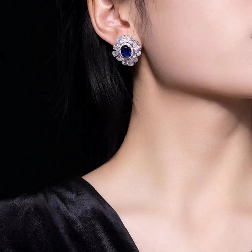 Lady wearing Blue sapphire silver earrings with moissanite halo