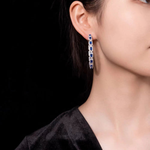 Lady wearing Blue sapphire silver drop earrings with moissanite