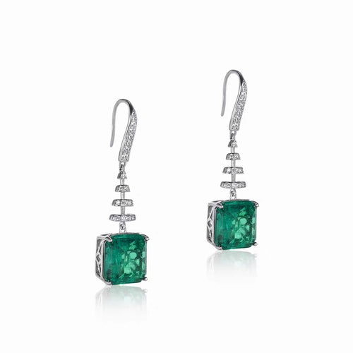 side view of Dangling emerald drop earrings in silver